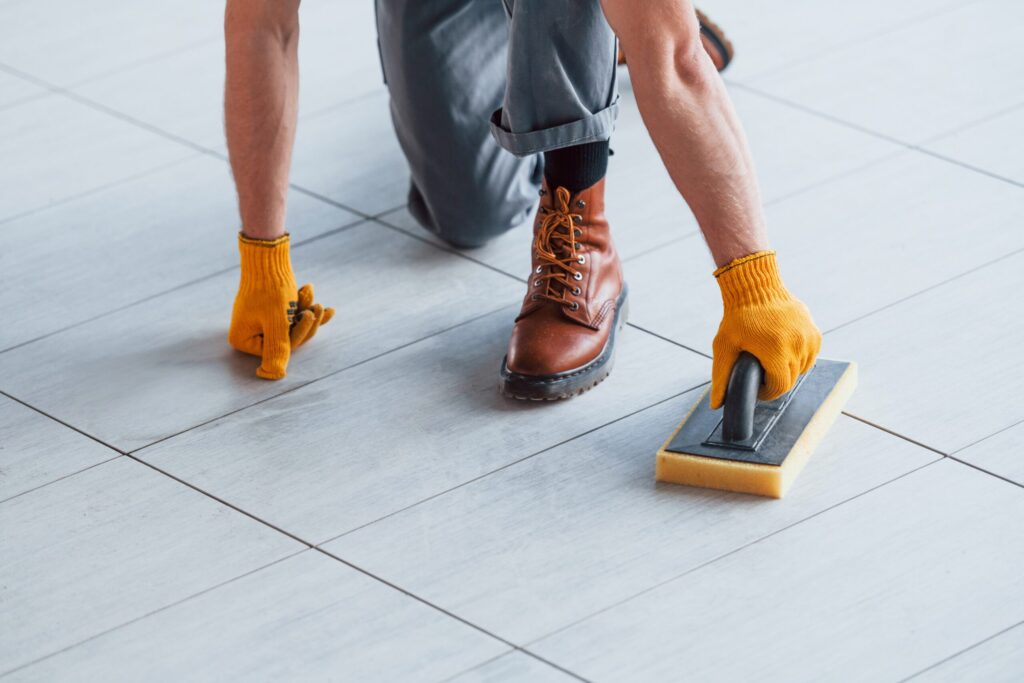 Worker cleaning porcelain tile joints with sponge tool for proper tile maintenance