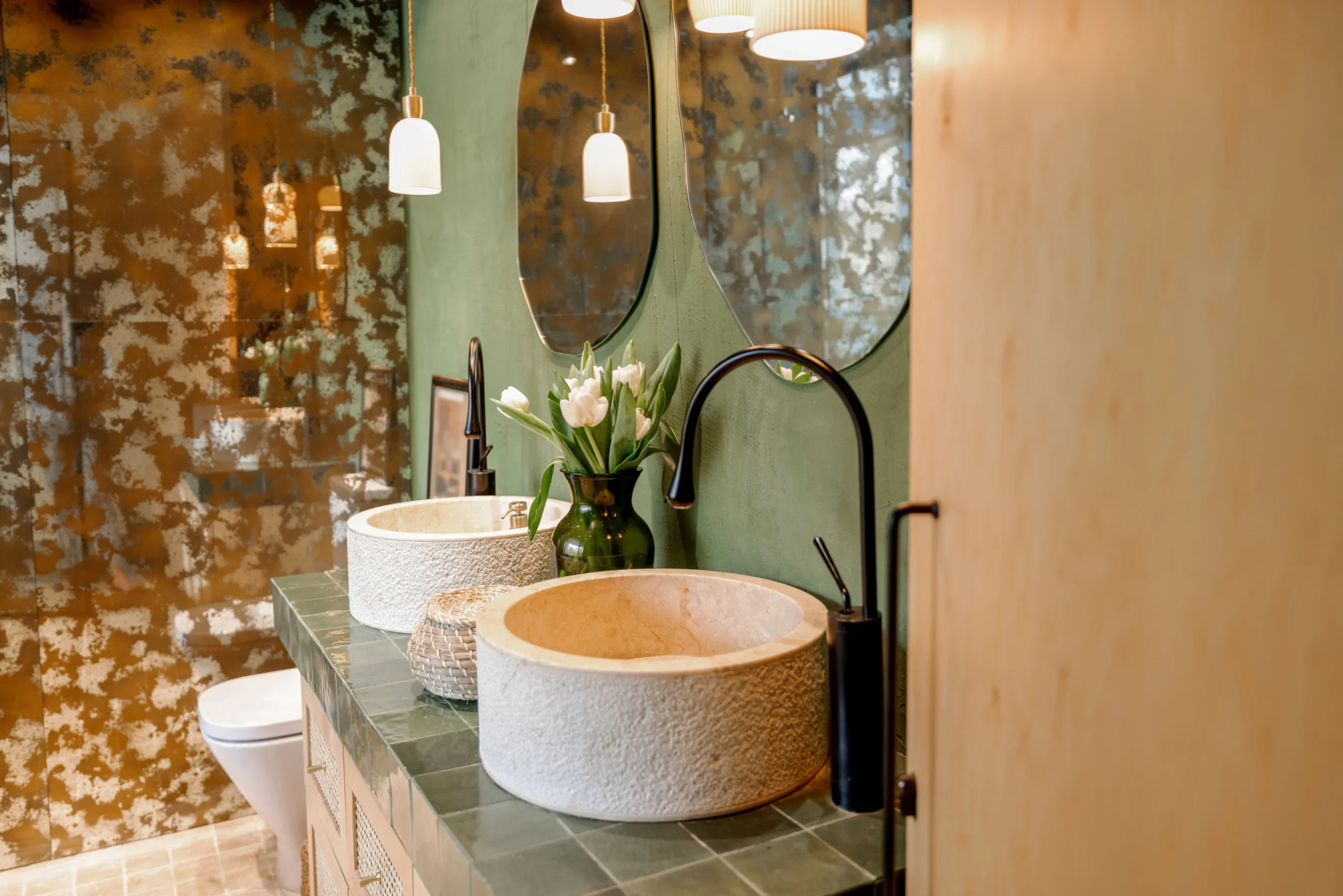 Modern bathroom with stone vessel sinks and green tile countertop in natural boho style