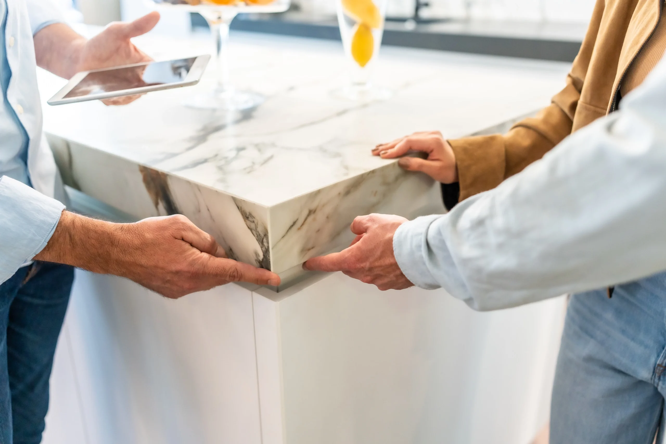 close-up of people inspecting a marble kitchen countertop edge for durability and design