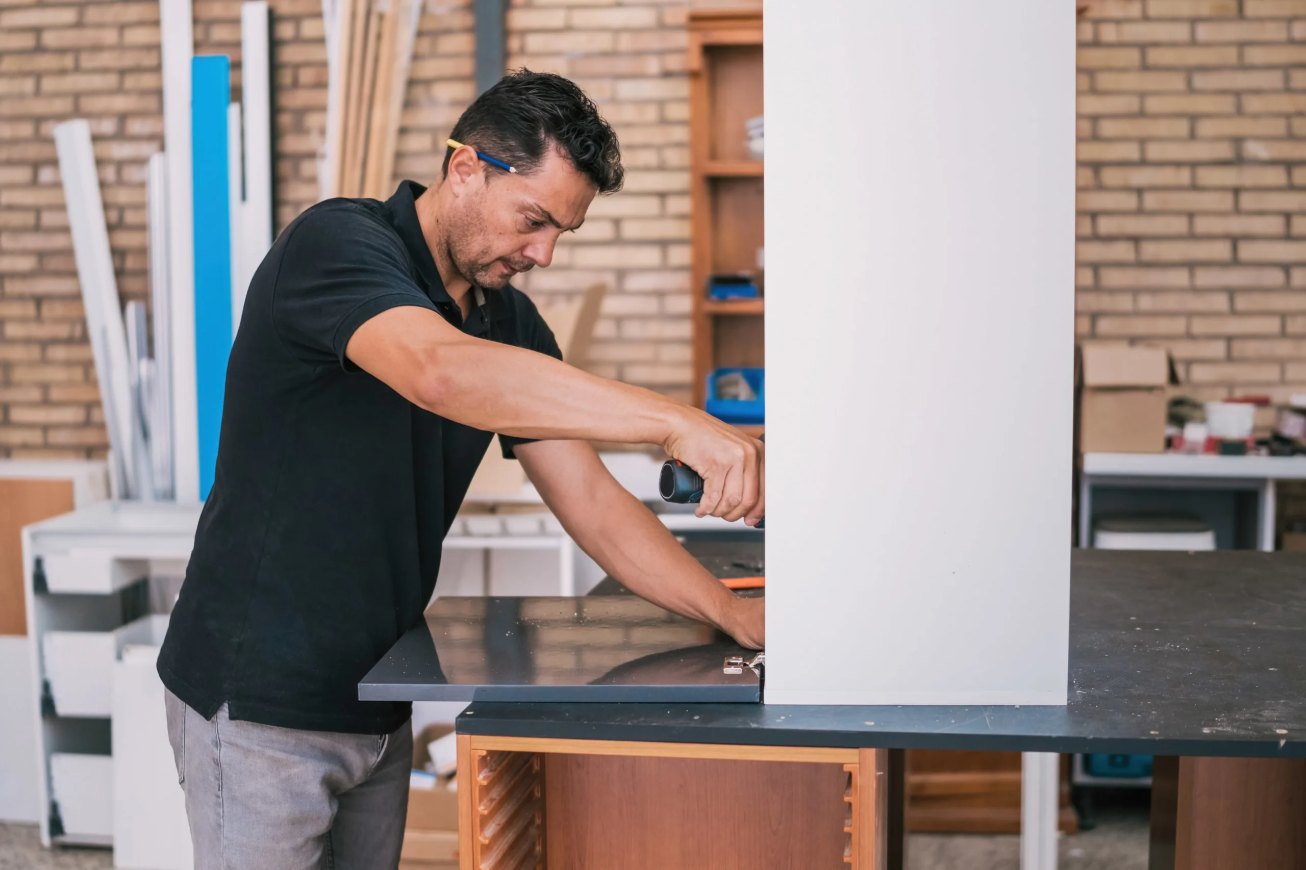 Carpenter using a drill to assemble a custom kitchen cabinet