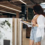 Woman selecting granite slabs in a showroom while holding a catalog