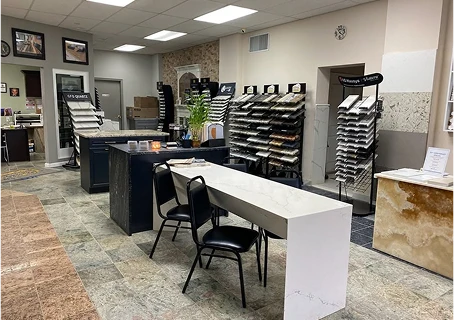 Modern showroom displaying countertop and tile samples with consultation area and display racks