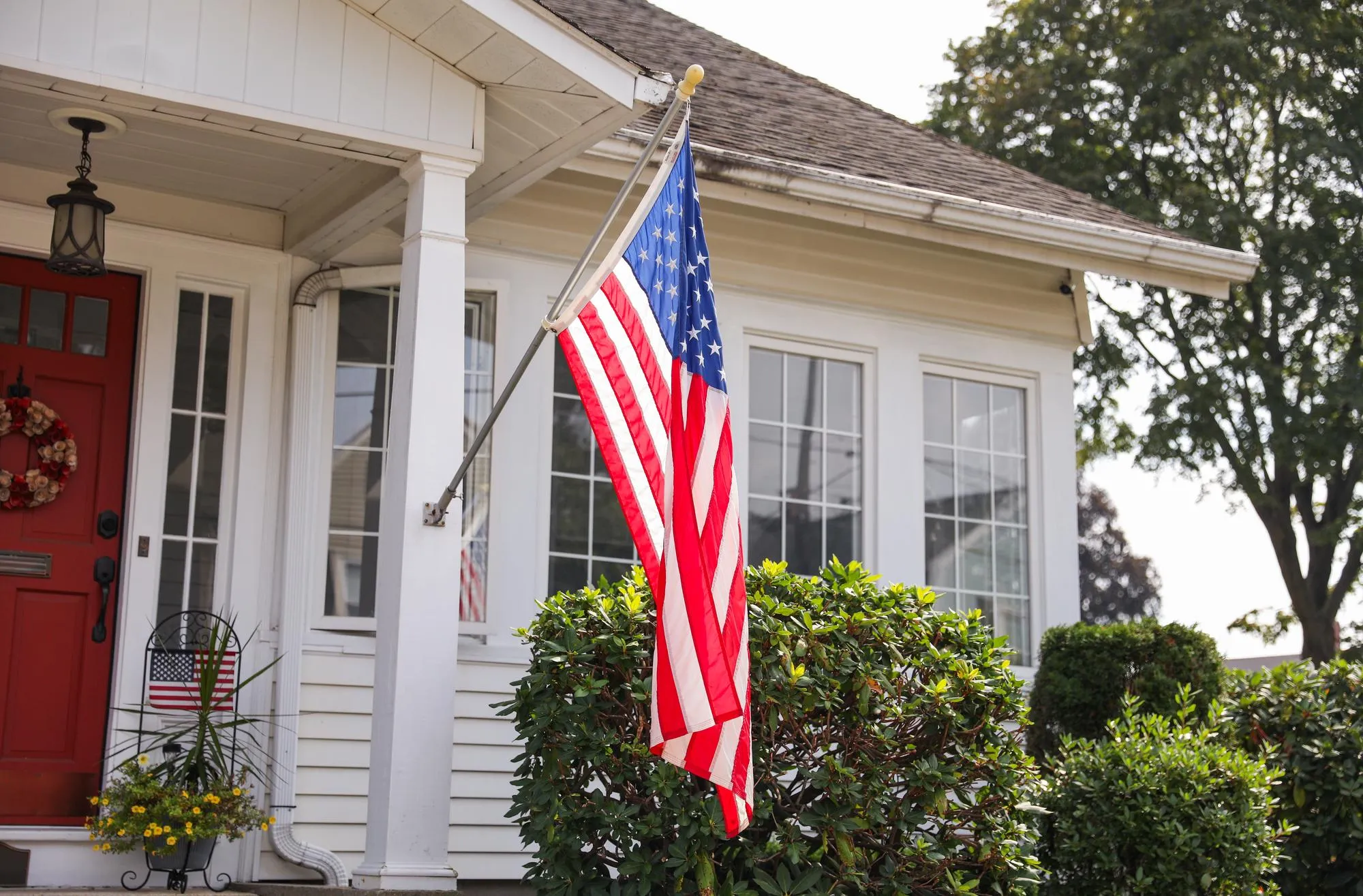 American flag displayed on the porch of a white residential house