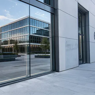 Modern office building exterior with floor-to-ceiling glass windows reflecting a neighboring building