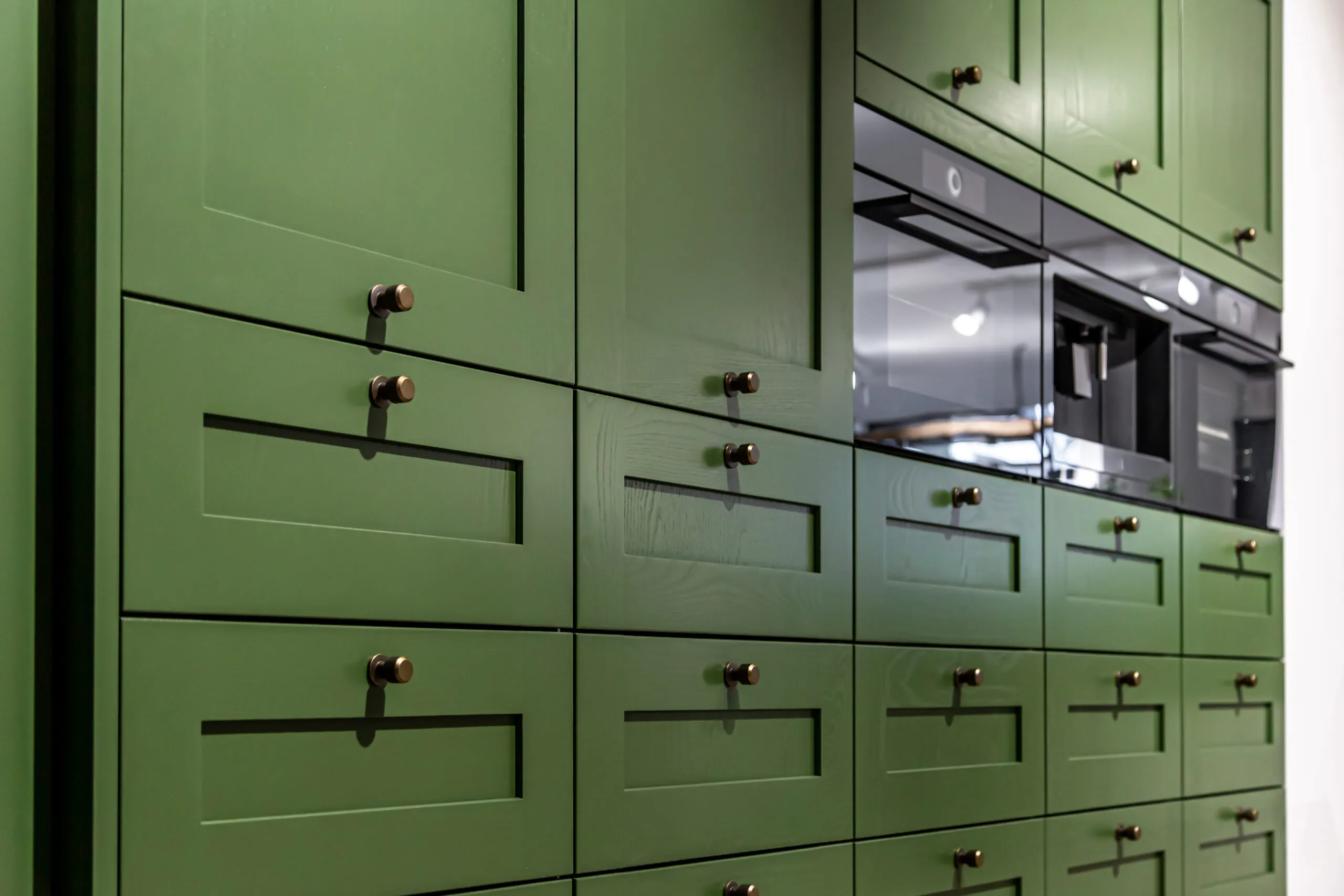 Green kitchen cabinets with modern shaker-style fronts and brass hardware, reflecting 2025 cabinet color trends.